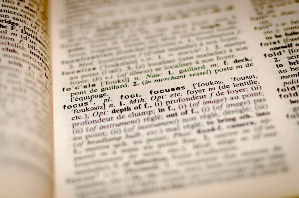 A close up macro shot of an open English dictionary page highlighting the word focus and its definitions.